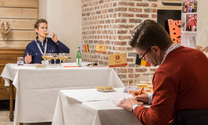Man proeft bier en man op de voorgrond maakt notities tijdens Brussels Beer Challenge